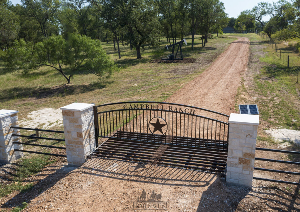 Ranch gate with custom letter and custom stone columns. gate powered by solar.