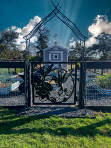 Metal art of hummingbird with sun peaking around horizon.