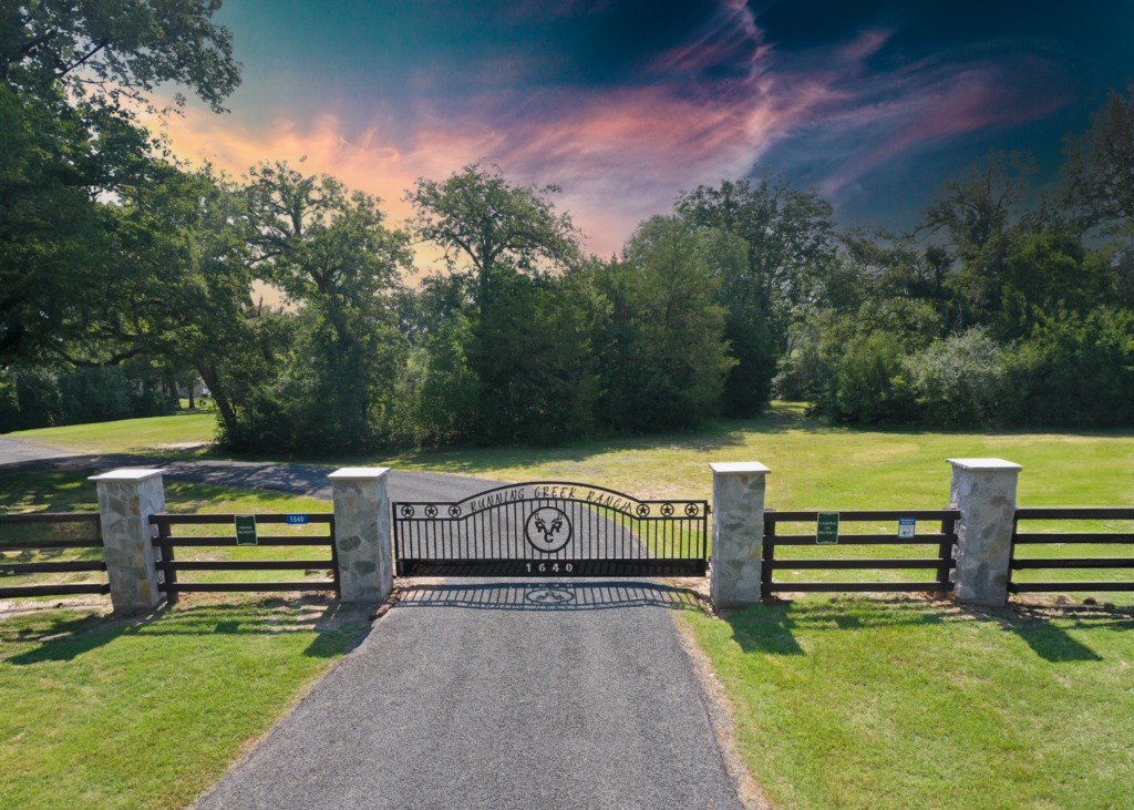 Multiple stone columns with custom metal lettering on a swing gate