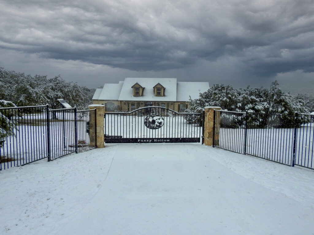 Snowy day with custom ranch gate with deer in center of gate