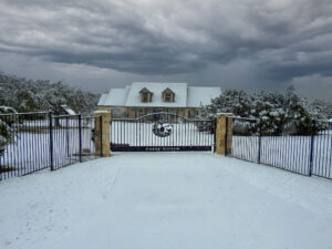 Snowy day with custom ranch gate with deer in center of gate