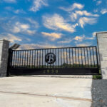 Stone columns with a swing gate between them with a circle and a letter B in the middle of gate.