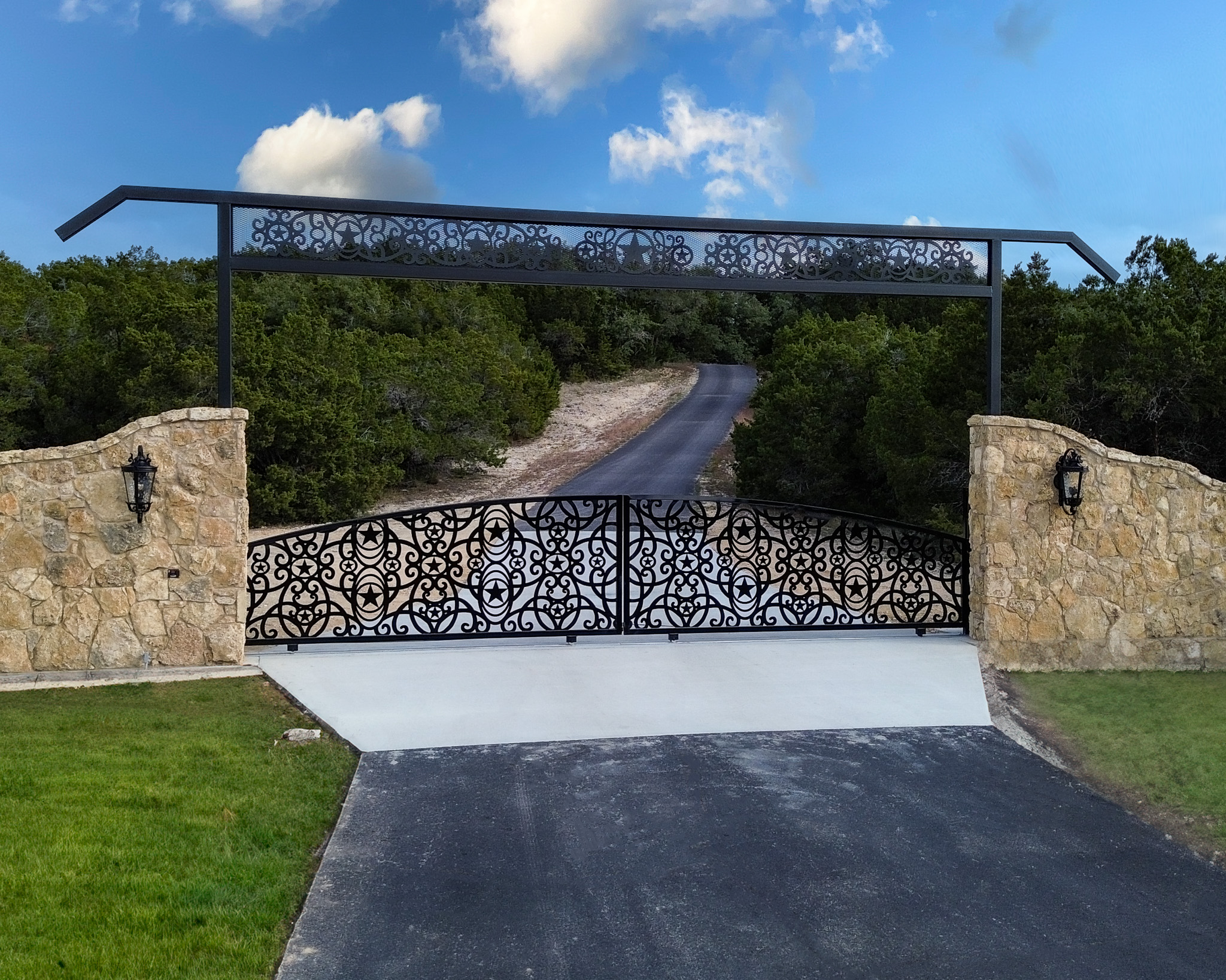 Texas sized entrance with two sliding gates with stars and circle/swirl art throughout gate and with same design in the overhead.