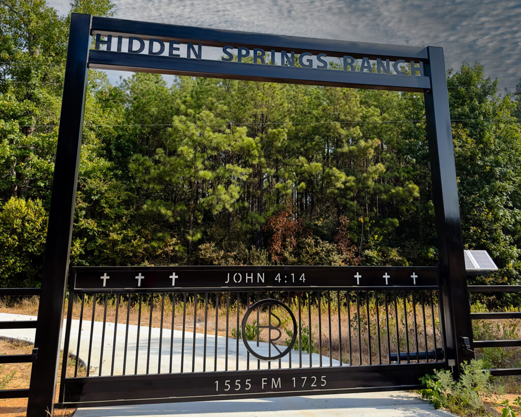 Ranch gate with Crosses on the top of the gate and custom circle logo in the middle.