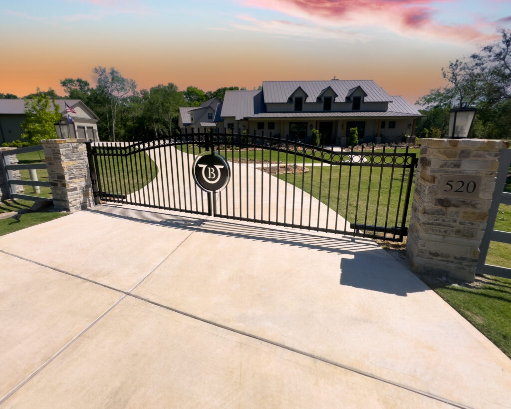 Double swing gates with custom logo in the center of the two with an arch on top of gate.