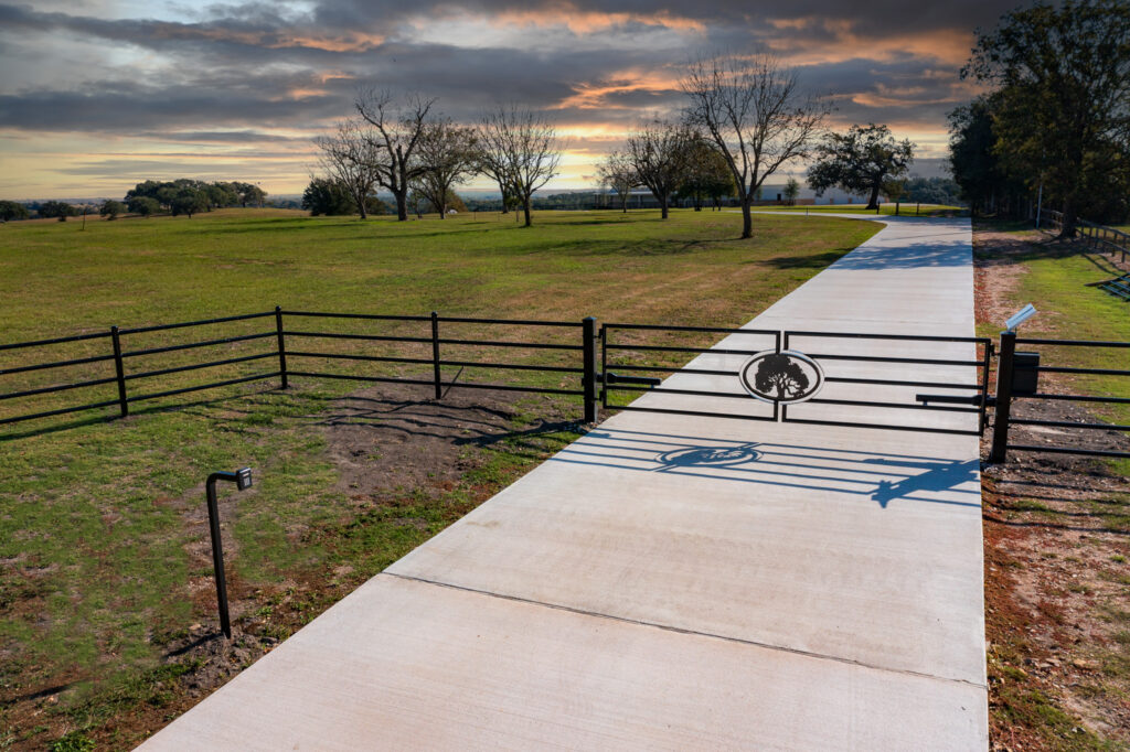 Pipe fencing with metal art with lone oak in center and gate automation