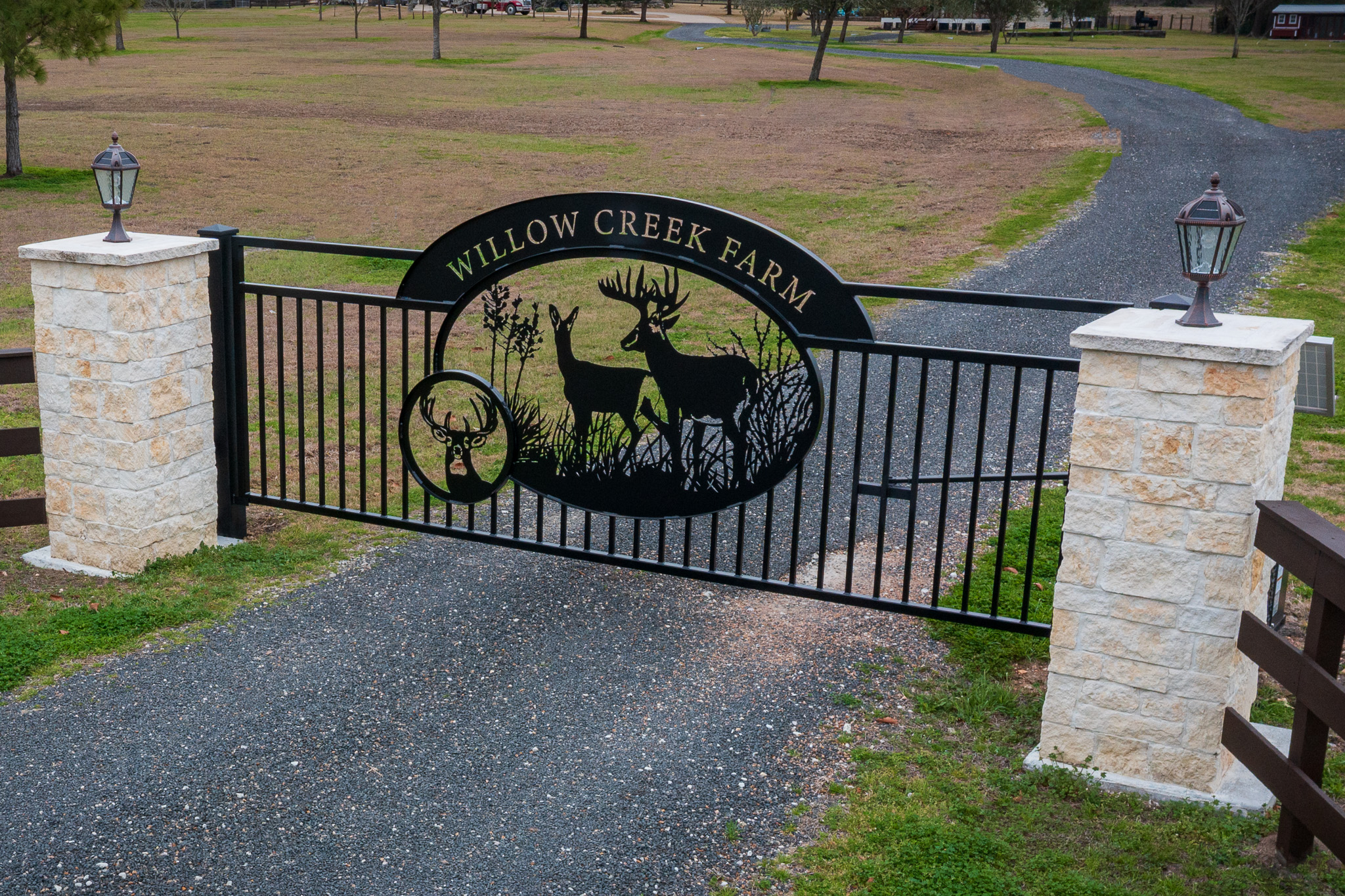 Stone columns with lighting fixed on top of columns and single swing gate